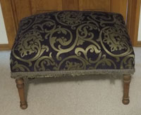 Small, low padded bench, hand-upholstered with rich blue & gold damask fabric